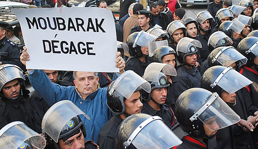 A protester holding a placard in French reading "Mubarak, get out" is surrounded by riot police during a demonstration in downtown Cairo, Egypt, Tuesday, Jan. 25, 2011. Anti-government protesters marched in the Egyptian capital chanting against President Hosni Mubarak and calling for an end to poverty. (AP Photo/Mohammed Abu Zaid)