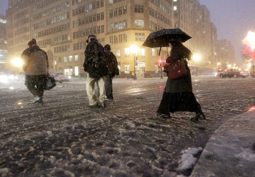 Commuters cross a street intersection of downtown Washington as snow begins to fall, Wednesday, Jan. 26, 2011. (AP Photo/Pablo Monsivais)