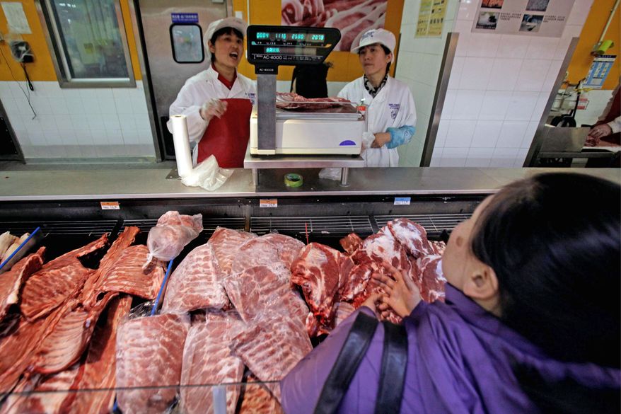 Supermarket workers weigh pork for a customer in Beijing. Clenbuterol stubbornly continues to pop up laced into animal feed by farmers impatient to get their meat to market and turn a profit. (Associated Press)