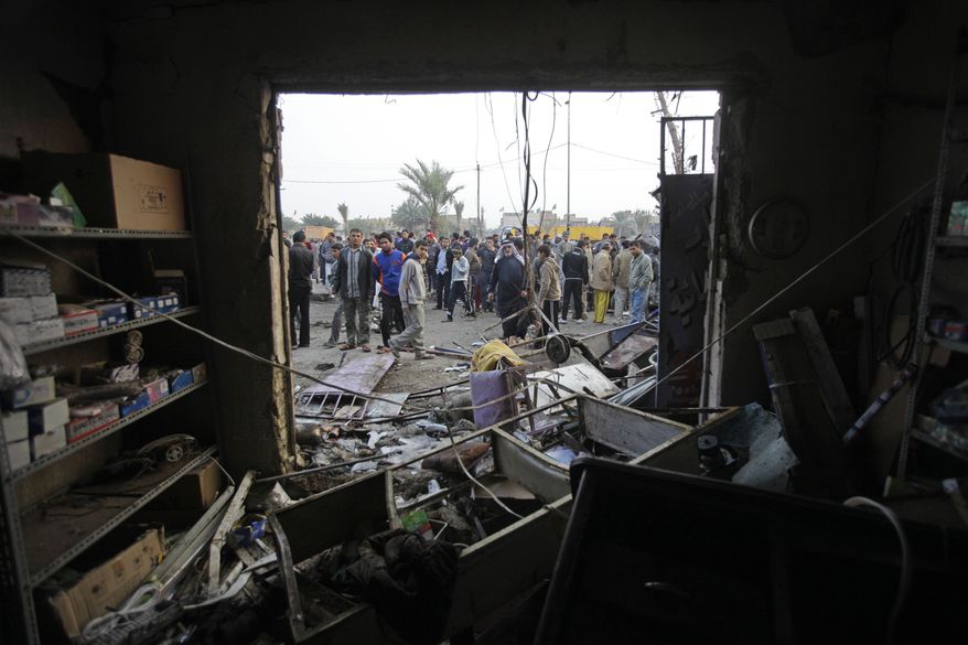 People gather around a destroyed shop at the scene of a car bomb attack in Baghdad, Iraq, on Thursday, Jan. 27, 2011. A car bomb ripped through a funeral tent in a mainly Shiite area of Baghdad on Thursday, killing and wounding scores of people and prompting scuffles between police and Iraqis angry about security failures. (AP Photo/Khalid Mohammed)