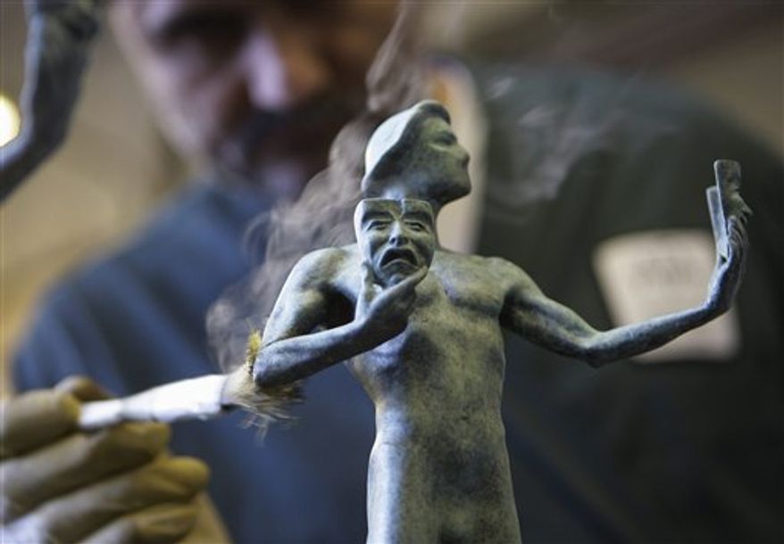 FILE - In this Jan. 21, 2011 file photo, craftsman Ricardo Godinez applies a green-black patina coating to a statuette being finished for the 17th Annual Screen Actors Guild Awards at the American Fine Arts Foundry in Burbank, Calif. The SAG Awards will be held in Los Angeles on Sunday, Jan. 30. (AP Photo/Damian Dovarganes)