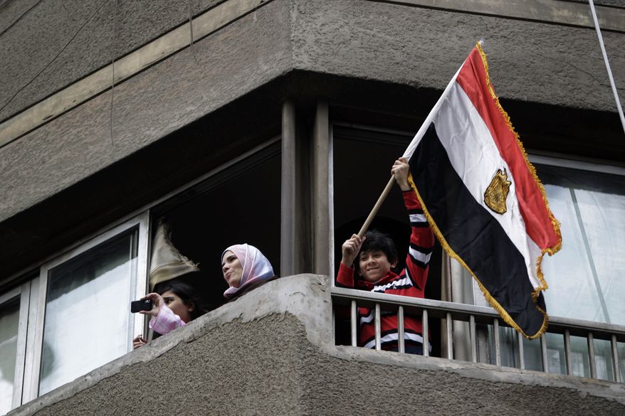 A youth waves an Egyptian flag as people watch from a balcony during a demonstration by anti-government activists, in Cairo Friday, Jan. 28, 2011. Tens of thousands of anti-government protesters poured into the streets of Egypt Friday, stoning and confronting police who fired back with rubber bullets and tear gas in the most violent and chaotic scenes yet in the challenge to President Hosni Mubarak's 30-year rule. (AP Photo/Ben Curtis)