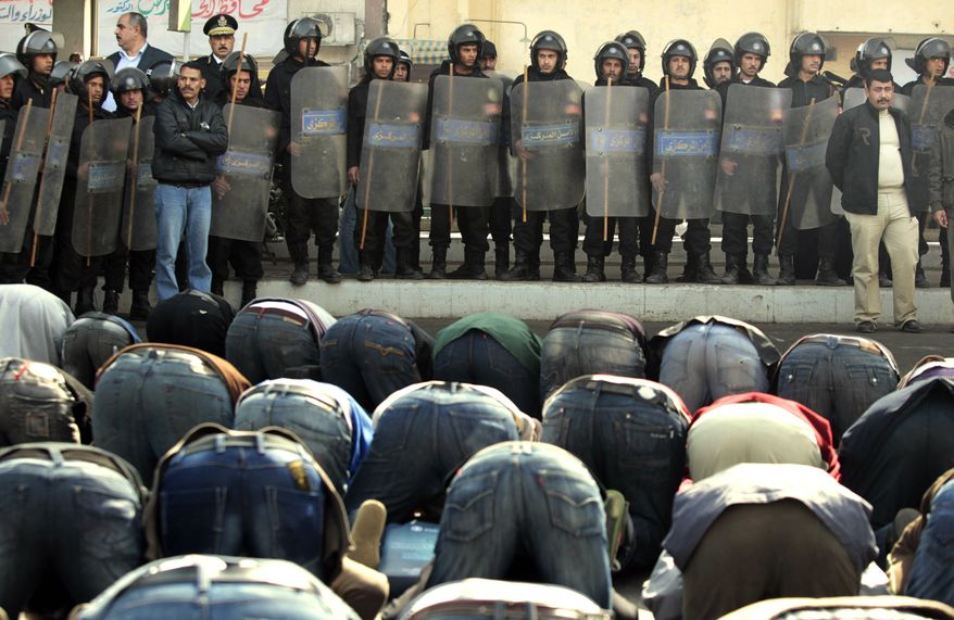 Egyptian riot police officers stand in front of protesters performing Friday prayers in Cairo Friday, Jan. 28, 2011. Tens of thousands of anti-government protesters poured into the streets of Egypt Friday, stoning and confronting police who fired back with rubber bullets and tear gas in the most violent and chaotic scenes yet in the challenge to President Hosni Mubarak's 30-year rule. (AP Photo/Lefteris Pitarakis)