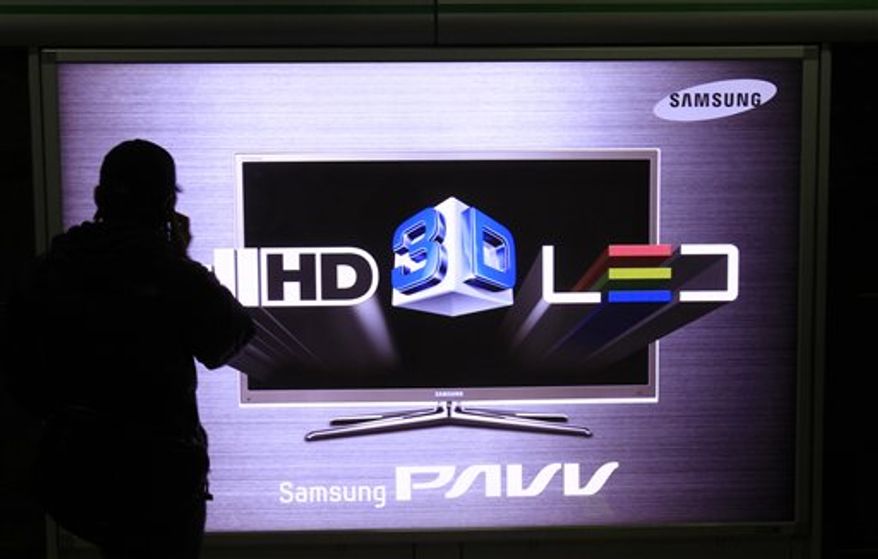 A man uses his mobile phone near the sign advertising Samsung Electronics Co's HD TV screen at a subway station in Seoul, South Korea, Friday, Jan. 28, 2011. Samsung Electronics said net profit rose 13 percent in the fourth quarter of 2010 amid higher sales of semiconductors and smartphones as the technology giant rounded out a record year for profits and revenue. (AP Photo/ Lee Jin-man)