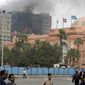The Egyptian museum is seen intact, right, as smoke billows from the ruling National Democratic party building, torched by anti government protesters overnight, in central Cairo, Egypt, on Saturday, Jan. 29, 2011. (AP Photo/Ben Curtis)