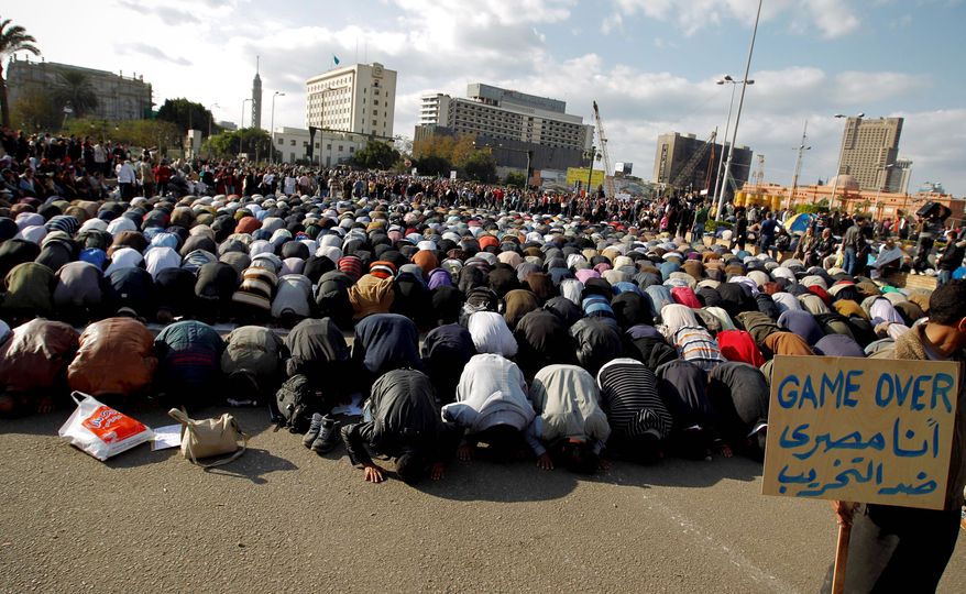 Anti-government protesters pray Monday at Tahrir Square in Cairo. A coalition of opposition groups called for a million people to take to Cairo's streets Tuesday. The Arabic on the sign reads "I'm Egyptian, anti-destruction." (Associated Press)