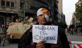 A wounded demonstrator carries a poster in Cairo on Monday. A coalition of protesters hopes Tuesday to increase the pressure on President Hosni Mubarak to resign. (Associated Press)