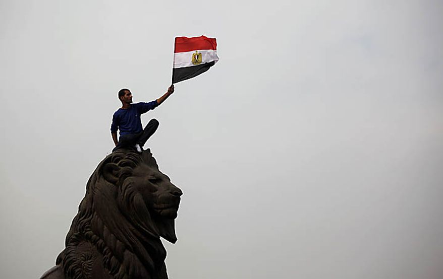 An Egyptian man waves the national flag atop a statue just outside Tahrir, or Liberation, Square in Cairo on Tuesday, Feb. 1, 2011. More than a quarter-million people flooded into the heart of the city, filling the the main square in by far the largest demonstration in a week of unceasing demands for President Hosni Mubarak to leave after nearly 30 years in power. (AP Photo/Emilio Morenatti)