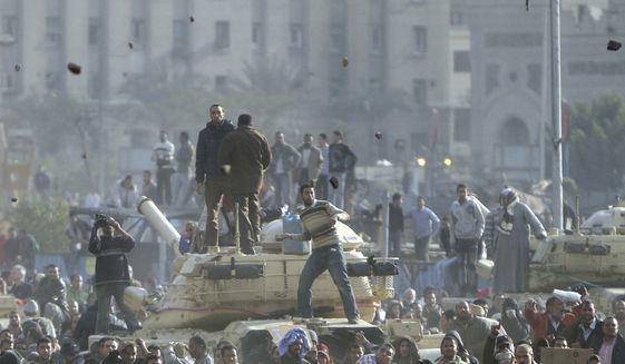 Stones fly through the air as supporters of President Hosni Mubarak, foreground, fight with anti-Mubarak protesters, rear, standing on army tanks in Cairo, Egypt, Wednesday, Feb.2, 2011. Several thousand supporters of Mr. Mubarak, including some riding horses and camels and wielding whips, clashed with anti-government protesters Wednesday as Egypt&#x27;s upheaval took a dangerous new turn. (AP Photo/Ahmed Ali)