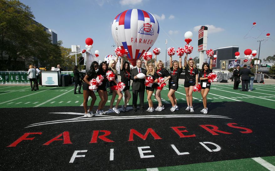 Paul Palsu, Farmers Insurance president, center, poses with Los Angeles Kings cheerleaders, Tuesday, Feb. 1, 2011, during a ceremony naming a new NFL stadium in Los Angeles. A proposed NFL stadium in downtown Los Angeles would be called Farmers Field under a 30-year naming-rights deal between developer AEG and Farmers Insurance Exchange. (AP Photo/Nick Ut)