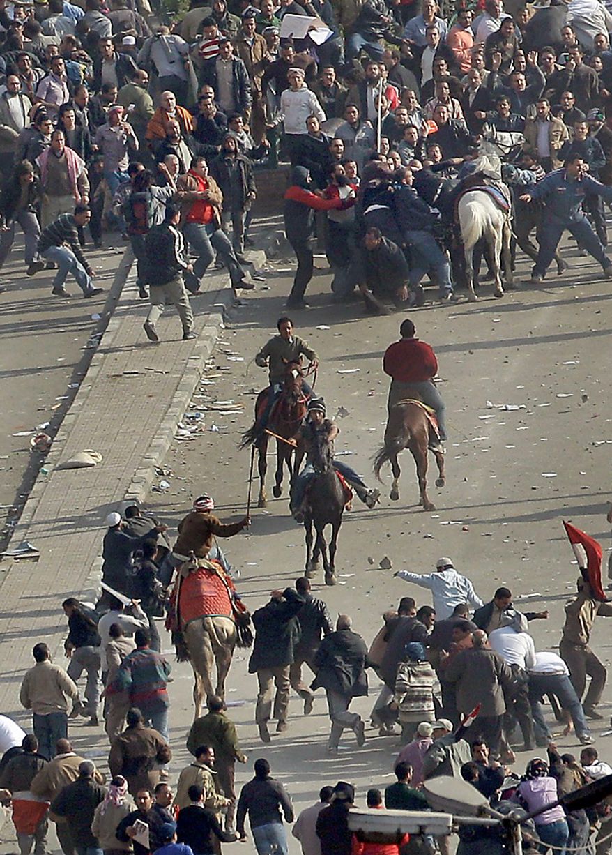 Pro-government demonstrators, below, some riding camels and horses and armed with sticks, clash with anti-government demonstrators, above, who pull one off his white horse and beat him, in Tahrir square, the center of anti-government demonstrations, in Cairo, Egypt, Wednesday, Feb. 2, 2011. (AP Photo/Ben Curtis)