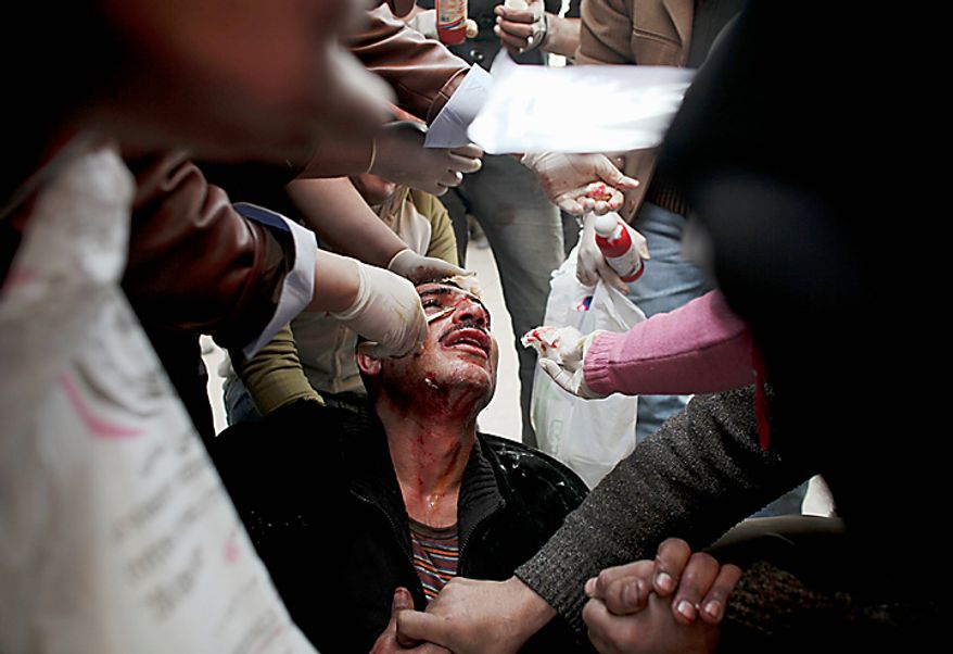 An injured anti-government protester sits on the ground as he is treated by medics during clashes in Tahrir, or Liberation, Square, in Cairo, Egypt, Wednesday, Feb. 2, 2011. Several thousand supporters of President Hosni Mubarak, including some riding horses and camels and wielding whips, clashed with anti-government protesters as Egypt's upheaval took a dangerous new turn. (AP Photo/Tara Todras-Whitehill)