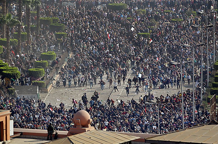 Pro-government demonstrators, below, clash with anti-government demonstrators, above, as an Egyptian Army soldier on the rooftop of the Egyptian Museum observes the scene in Tahrir Square, the center of anti-government demonstrations, in Cairo, Egypt, Wednesday, Feb. 2, 2011. (AP Photo/Ben Curtis)