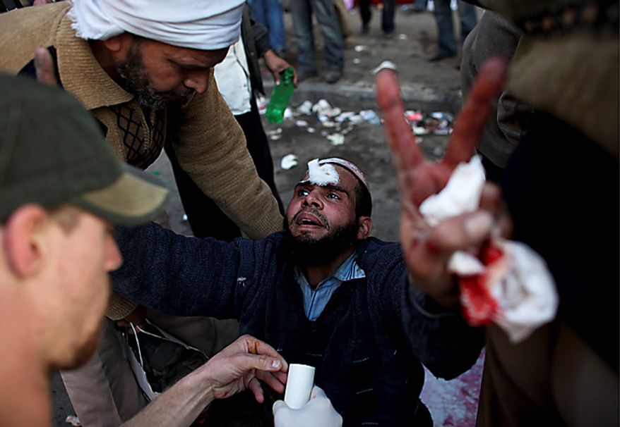 An injured anti-government protester gestures as he is treated by medics during clashes in Tahrir, or Liberation, Square, in Cairo, Egypt, Wednesday, Feb. 2, 2011. Several thousand supporters of President Hosni Mubarak clashed with anti-government protesters as Egypt's upheaval took a dangerous new turn. (AP Photo/Tara Todras-Whitehill)
