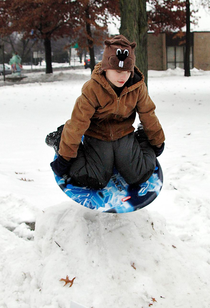 Ethan Watt, 7, wears a groundhog hat as he slides on a saucer down a mound of snow his father piled up for him and his brother at a park in Punxsutawney, Pa., on Tuesday, Feb. 1, 2011. Thousands of people gathered in the small Pennsylvania town in anticipation of the annual gathering at Gobbler's Knob for Groundhog Day. (AP Photo/Keith Srakocic)
