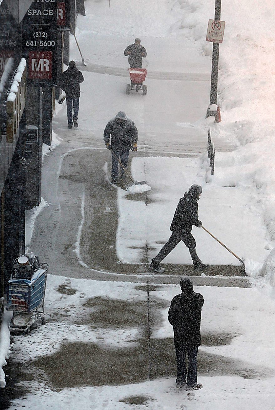 Workers clear the sidewalk during a blizzard Wednesday, Feb. 2, 2011, in Chicago. Forecasts call for snow accumulation between one and two feet. (AP Photo/Charles Rex Arbogast)
