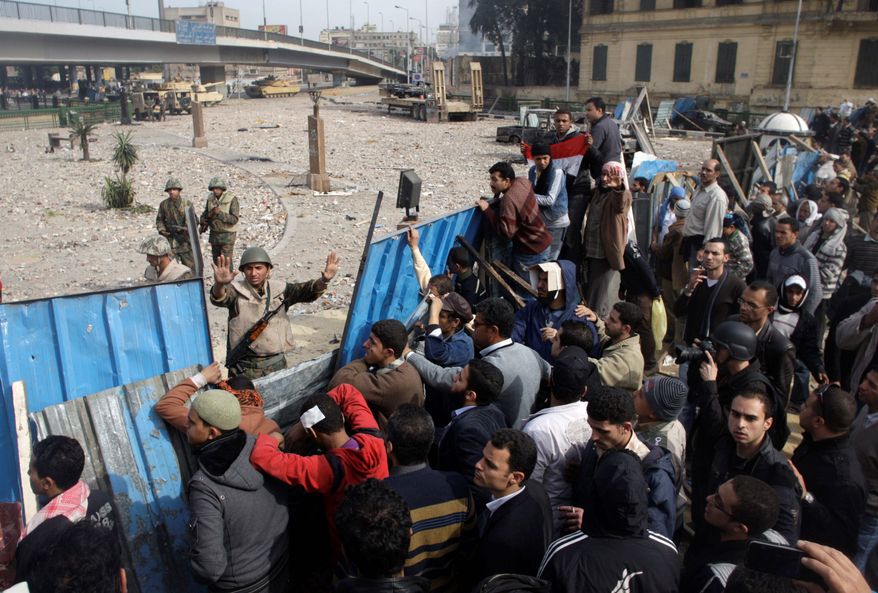 A soldier tries to halt protesters just outside Cairo's main square Thursday. The protesters accuse the regime of sending a force of paid thugs and policemen in civilian clothes to attack them. (Associated Press)