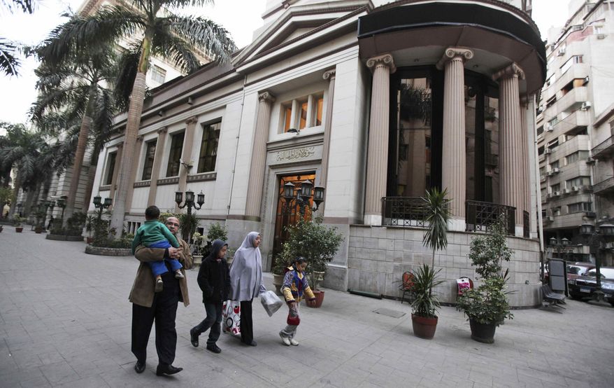 ** FILE ** An Egyptian family walks past the closed stock exchange building in downtown Cairo on Thursday, Jan. 27, 2011. The protests that have engulfed Cairo since Jan. 25 have shuttered businesses, forced factories to stop operating, closed banks and the stock exchange, and limited suppliers' ability to restock store shelves. (AP Photo/Victoria Hazou, File)