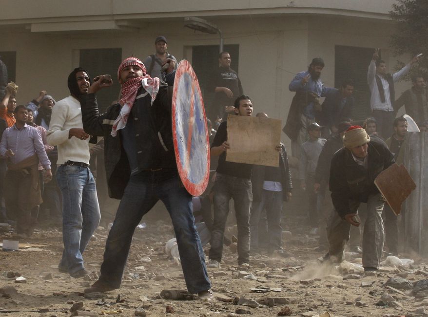 Egyptian anti-government protesters throw stones during clashes in downtown Cairo, Egypt, Thursday, Feb. 3, 2011. New clashes are heating up again and shots are being fired in the air around Cairo's central Tahrir Square as anti-government protesters push back regime supporters. (AP Photo/Khalil Hamra)