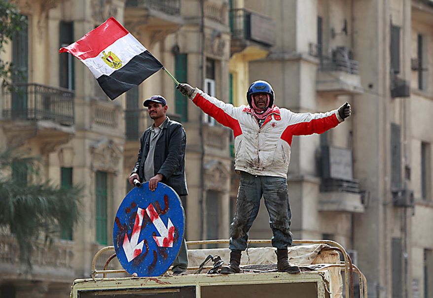 An anti-government protester waves the national flag in Cairo's main square Thursday, Feb. 3, 2011. Egyptian army tanks and soldiers moved to end violence between anti-government protesters and supporters of President Hosni Mubarak in Cairo's central square on Thursday after standing by for nearly a day as the two sides battled with rocks, sticks, bottles and firebombs. (AP Photo/Ben Curtis)