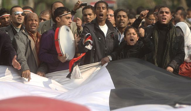 Protesters carry a giant Egyptian flag in front of the country&#x27;s parliament in Cairo on Wednesday in the anti-Mubarak movement&#x27;s first expansion outside Tahrir Square. The demonstrators chanted slogans demanding the dissolution of the legislative body, which is controlled almost entirely by the ruling party. (Associated Press)