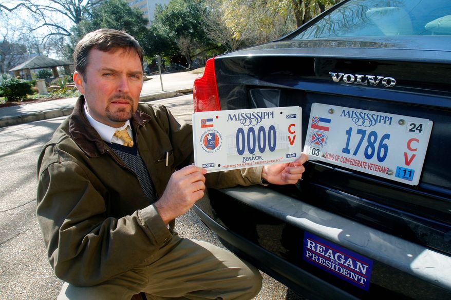 Greg Stewart, a member of the Sons of Confederate Veterans, displays a sample of the latest Civil War sesquicentennial tag that is being sold (left), adjacent to the current tag. A fight is brewing over a proposal for a license plate honoring an early leader of the Ku Klux Klan. (Associated Press)