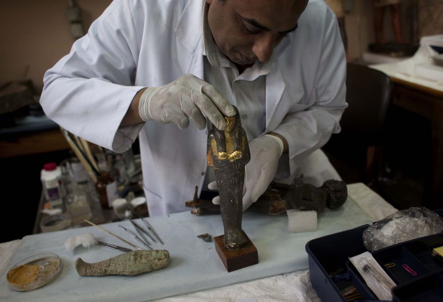 An Egyptian restorer fixes one the pieces that was broken by looters at the Egyptian Museum in Cairo, Egypt, on Thursday, Feb. 10, 2011. Would-be looters broke into Cairo's famed Egyptian Museum on Saturday, Jan. 29, ripping the heads off two mummies and damaging about 75 small artifacts before being caught and detained by army soldiers. (AP Photo/Emilio Morenatti)