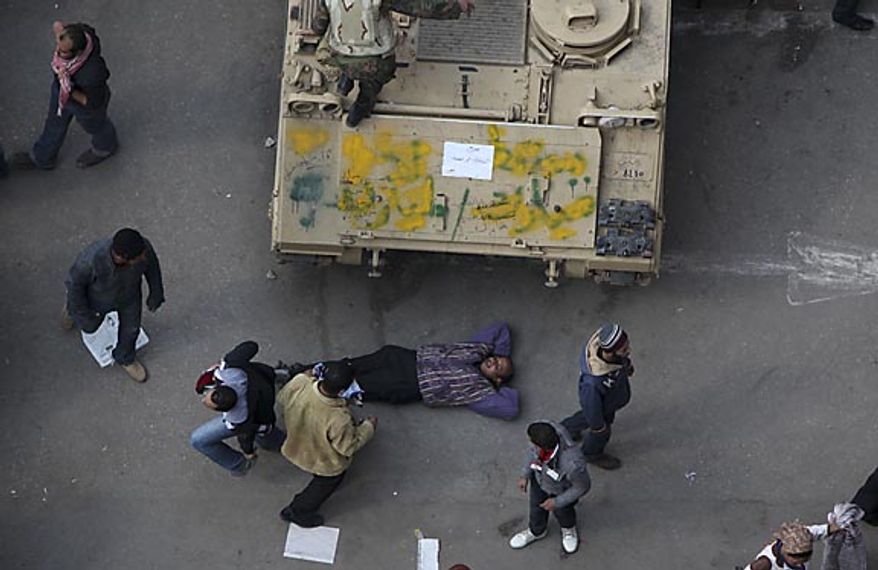 An anti-government protester lies down near an Egyptian army vehicle after traditional Muslim Friday prayers in Tahrir Square in downtown Cairo Friday, Feb. 11, 2011. The Egyptian government announced later Friday that President Hosni Mubarak has stepped down. (AP Photo/Tara Todras-Whitehill)