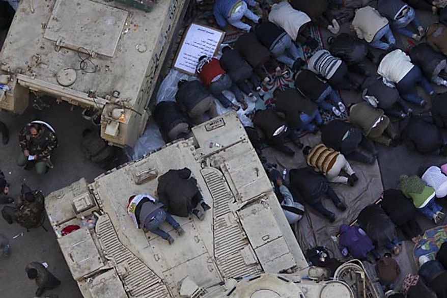 Anti-government protesters pray atop an Egyptian army vehicle in Tahrir Square in downtown Cairo Friday, Feb. 11, 2011. The Egyptian government announced later Friday that President Hosni Mubarak has stepped down. (AP Photo/Tara Todras-Whitehill)