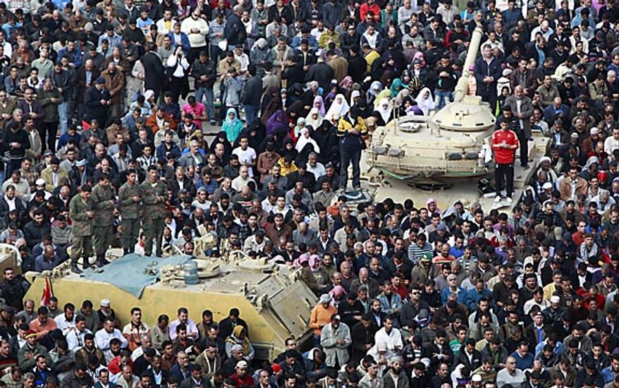 Anti-government protesters as well as Egyptian army soldiers on top of their vehicles, participate in traditional Muslim Friday prayers in Tahrir Square in downtown Cairo Friday, Feb. 11, 2011. The government announced later Friday that President Hosni Mubarak has stepped down. (AP Photo/Ben Curtis)