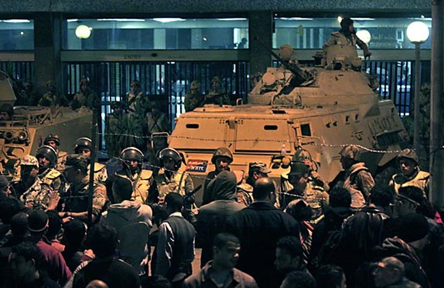 Army soldiers stand guard as anti-government protesters surround the state television building following Egyptian President Hosni Mubarak's televised speech, on the Corniche in downtown Cairo, Egypt Thursday, Feb. 10, 2011. The government announced Friday that Mr. Mubarak has stepped down. (AP Photo/Mohammed Abu Zaid)