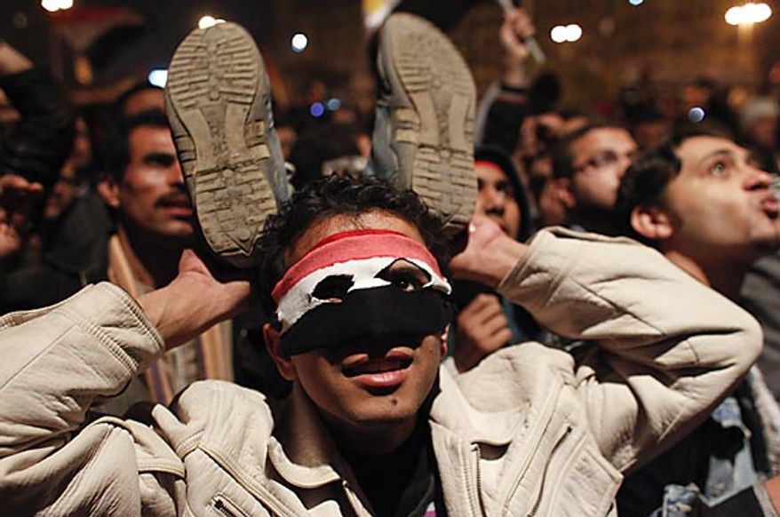 An anti-government protester in Cairo's Tahrir Square holds up his shoes in response to Egyptian President Hosni Mubarak's televised statement to the nation Thursday, Feb. 10, 2011. Mr. Mubarak stepped down Friday. (AP Photo/Tara Todras-Whitehill)