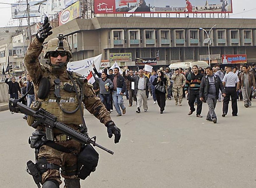 An Iraqi army soldier attempts to prevent photographers from taking pictures while protesters chant anti-government slogans during a demonstration in Baghdad, Iraq, Friday, Feb. 11, 2011. In at least four morning demonstrations across Baghdad, protesters painted a picture of their homeland that they said has fewer services and more corruption than in Egypt. (AP Photo/Khalid Mohammed)