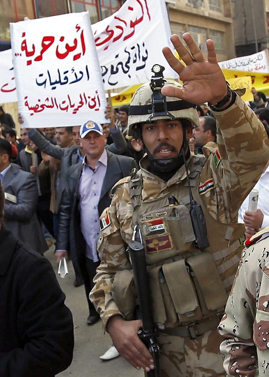 An Iraqi army soldier attempts to prevent photographers from taking pictures while protesters chant anti-government slogans during a demonstration in Baghdad, Iraq, Friday, Feb. 11, 2011. In at least four morning demonstrations across Baghdad, protesters painted a picture of their homeland that they said has fewer services and more corruption than in Egypt. The banners in Arabic read, "From Cairo to Baghdad, no for corruption" and "Maliki, like Saddam he does not care about orphans." (AP Photo/Hadi Mizban)