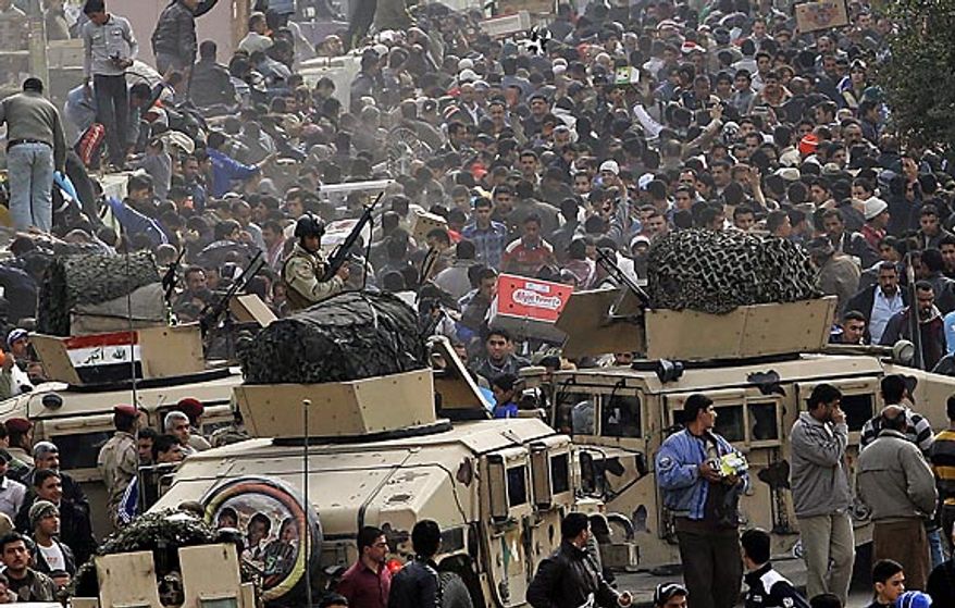 Iraqi army soldiers stand guard while protesters chant anti-government slogans during a demonstration in Baghdad, Iraq, Friday, Feb. 11, 2011. In at least four morning demonstrations across Baghdad, protesters painted a picture of their homeland that they said has fewer services and more corruption than in Egypt. (AP Photo/Hadi Mizban)