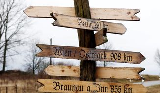 A handcrafted wooden signpost in Jamel, Germany, shows the way to Vienna, Paris and Braunau am Inn, the birthplace of Adolf Hitler in Austria.