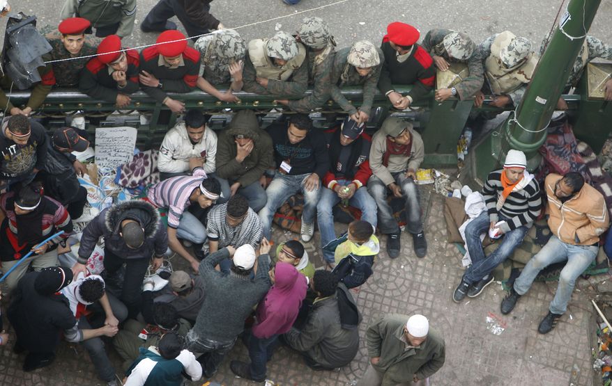 Military police and soldiers surround remaining protesters while trying to clear Tahrir Square in Cairo on Monday, Feb. 14, 2011. Egypt's military rulers dissolved parliament Sunday, suspended the constitution and promised elections in moves cautiously welcomed by pro-democracy protesters. (AP Photo/Hussein Malla)