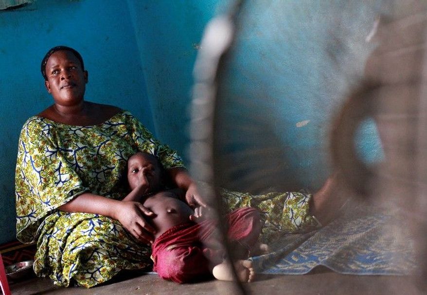 Diaby Madoussou holds one of her five children in their house in Abidjan. She has been waiting two months to have the body of her husband released to her. (Associated Press)