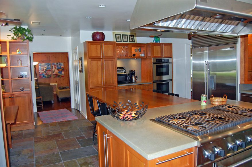 The renovated kitchen has concrete counters and custom-designed cherry cabinets. The custom-designed dining table will convey.