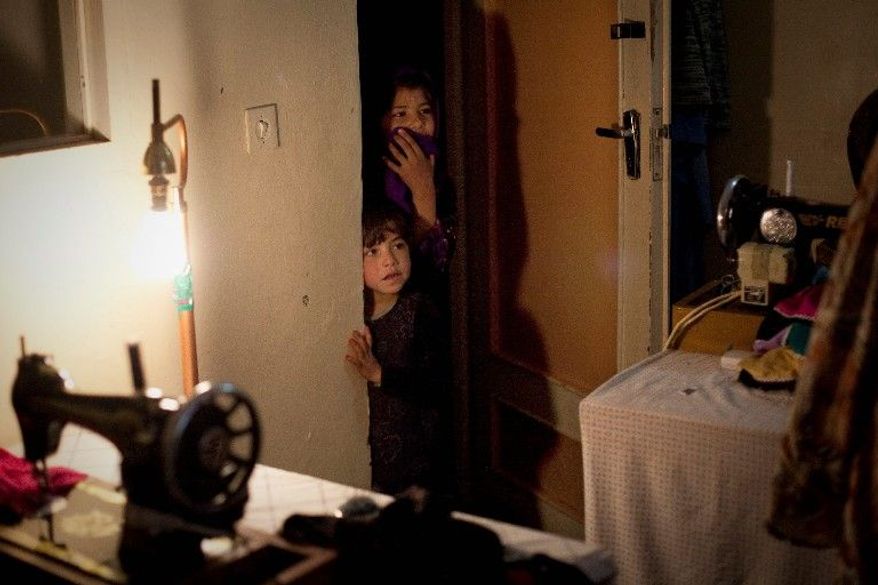 Children peer from a doorway at a women's charity organization in Kandahar. Security has been difficult to maintain in the war-torn city, despite the longtime presence of NATO troops. (Associated Press)