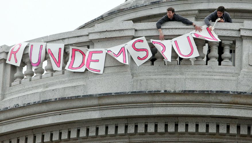 Two protesters put up a sign at the state Capitol in Madison, Wis., on Thursday, that reads "Run Dems Run" in support of 14 senators who fled the state. (Associated Press)