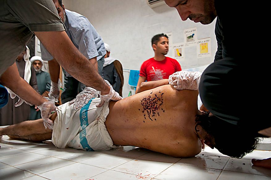In this picture taken Tuesday Feb. 15, 2011, the body of 20-year-old Ali Abdul Hadi Mushaima, alledgedly killed in clashes with security forces Monday, is prepared for burial in Daih, Bahrain. He was one of two people killed Monday in the protests demanding sweeping political reforms. On Thursday, according to medical officials four more people were killed after riot police drove protesters from a main square in Manama. (AP Photo/James Lawler Duggan)