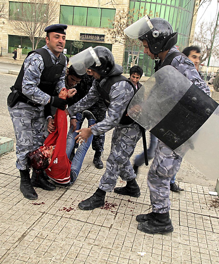 Iraqi riot police officers carry the body of a protester in front of the headquarters of Kurdish President Massoud Barzani's political party in Sulaimaniyah, 160 miles northeast of Baghdad Thursday, Feb. 17, 2011. Kurdish security forces opened fire on a crowd of protesters surrounding the headquarters of the party affiliated with the Kurdish president. (AP Photo/Yahya Ahmed)