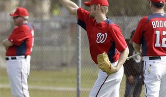 Washington Nationals right fielder Bryce Harper holds a football as part of a drill as he waits to chase a fly ball during a spring training baseball workout Tuesday, Feb. 22, 2011, in Viera, Fla. (AP Photo/David J. Phillip)