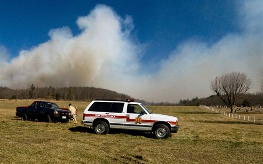 Firefighters are stationed on a hill below a 300-acre wildfire in the woods off of Rawley Pike near Harrisonburg, Va., on Saturday, Feb. 19, 2011. (AP Photo/Daily News-Record, Traci White)