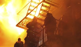 Firefighters stand on a fire escape as winds whip the flames from a five-alarm fire in the Brooklyn borough of New York late on Saturday, Feb. 19, 2011. The strong winds meant several hours of work for hundreds of New York firefighters trying to extinguish the fire, which ripped through the six-story apartment building. At least 20 firefighters were injured, authorities said. (AP Photo/Paul Martinka)