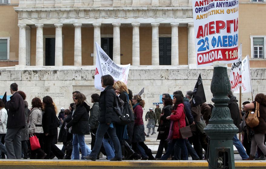 Striking teachers protest outside the Greek parliament on Syntagma Square in central Athens on Tuesday, Feb. 22, 2011. In front is a sign calling for a general strike on Wednesday, which disrupted flights and crippled public transport and other services as unions stepped up their opposition to austerity measures in the crisis-hit country. (AP Photo/Petros Giannakouris)