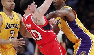 Los Angeles Lakers forward Ron Artest, right, give Atlanta Hawks guard Mike Bibby (10) a forearm block for a foul as lakers guard Derek Fisher (2) watches during the first half of an NBA basketball game, Tuesday, Feb. 22, 2011, in Los Angeles. (AP Photo/Alex Gallardo)