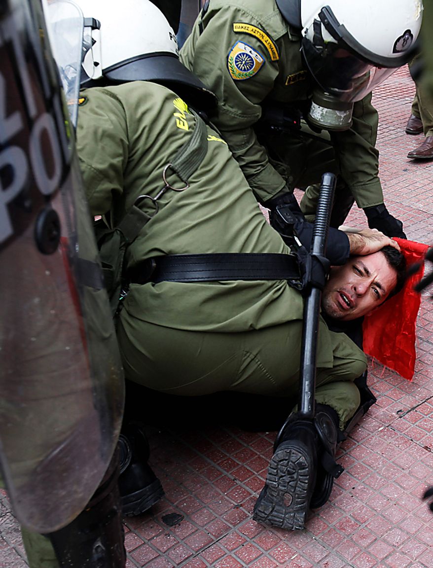 Riot police detain a protester during clashes in Athens on Wednesday, Feb. 23, 2011. Scores of youths hurled rocks and petrol bombs at riot police after clashes broke out during a mass rally taking place as part of a general strike. (AP Photo/Kostas Tsironis)