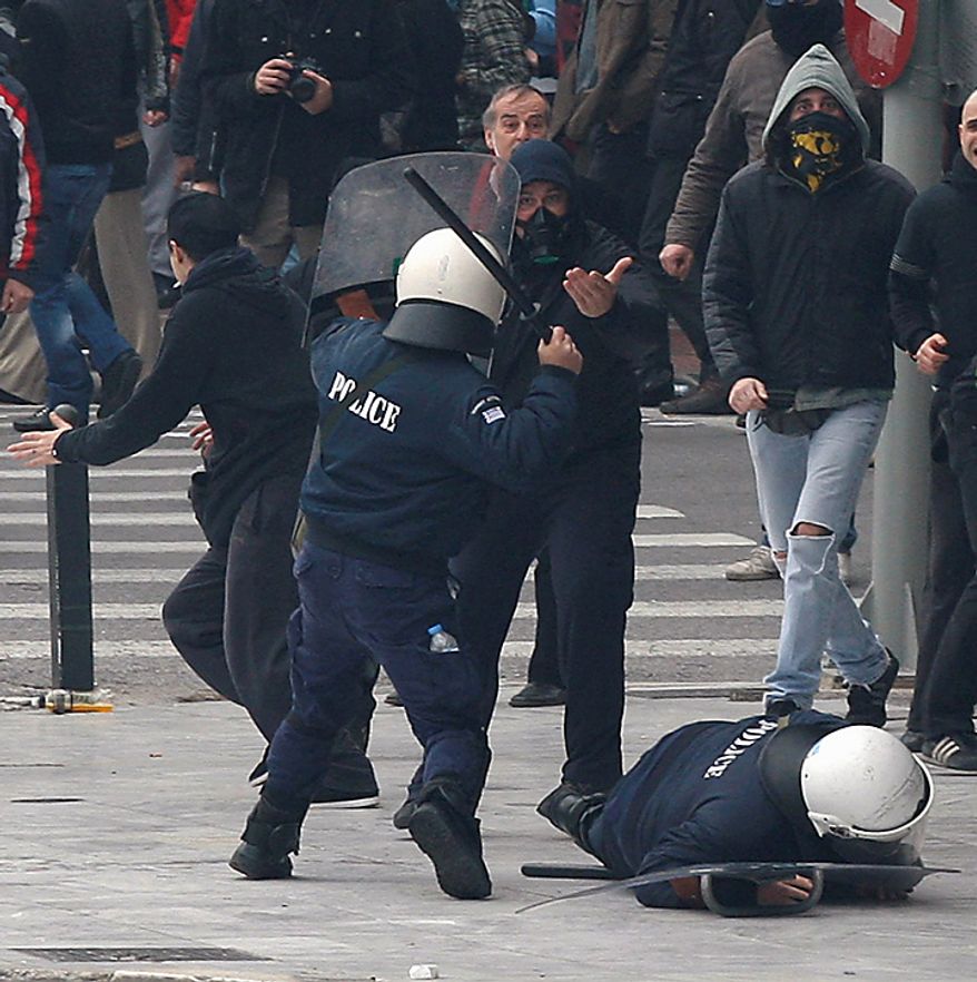 A riot policeman clashes with protesters as his colleague falls down during clashes in Athens on Wednesday, Feb. 23, 2011. Scores of youths hurled rocks and petrol bombs at police after clashes broke out during a mass rally taking place as part of a general strike. (AP Photo/Thanassis Stavrakis)
